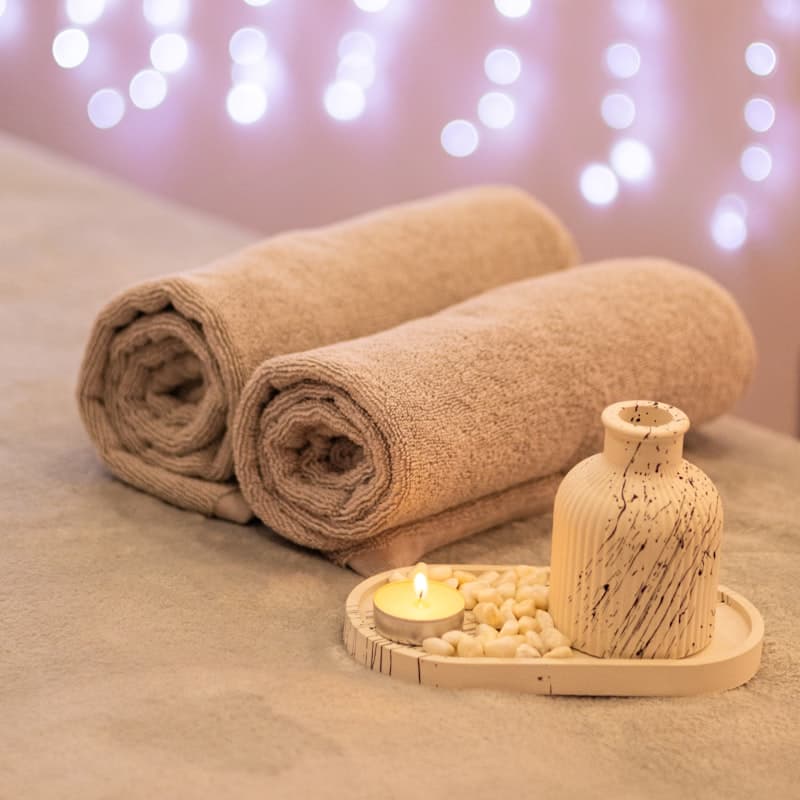 Rolled spa towels beside a candle and vase
